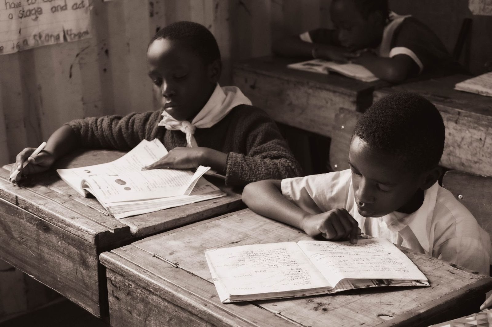 Student writing at a desk reviewing a paper draft